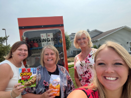 Employees standing in front of blessing box with food items